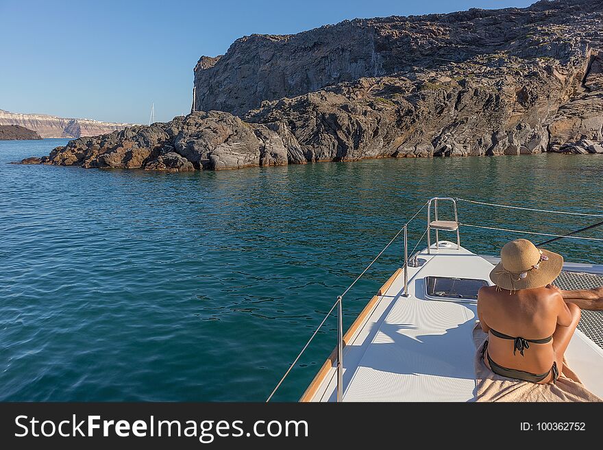Woman sitting on the bow of boat, santorini greece