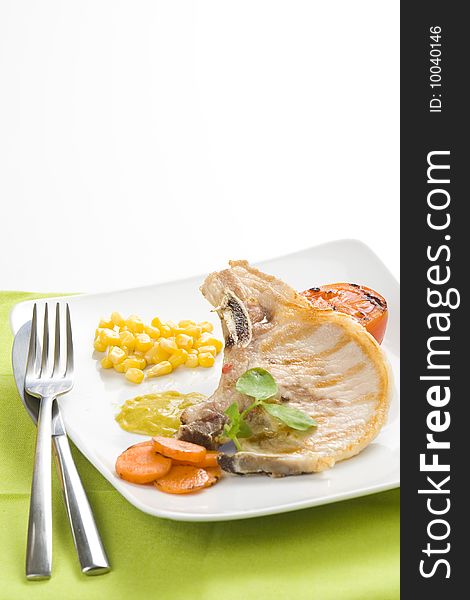 Tasty pork chop with corn carrot tomato isolated
