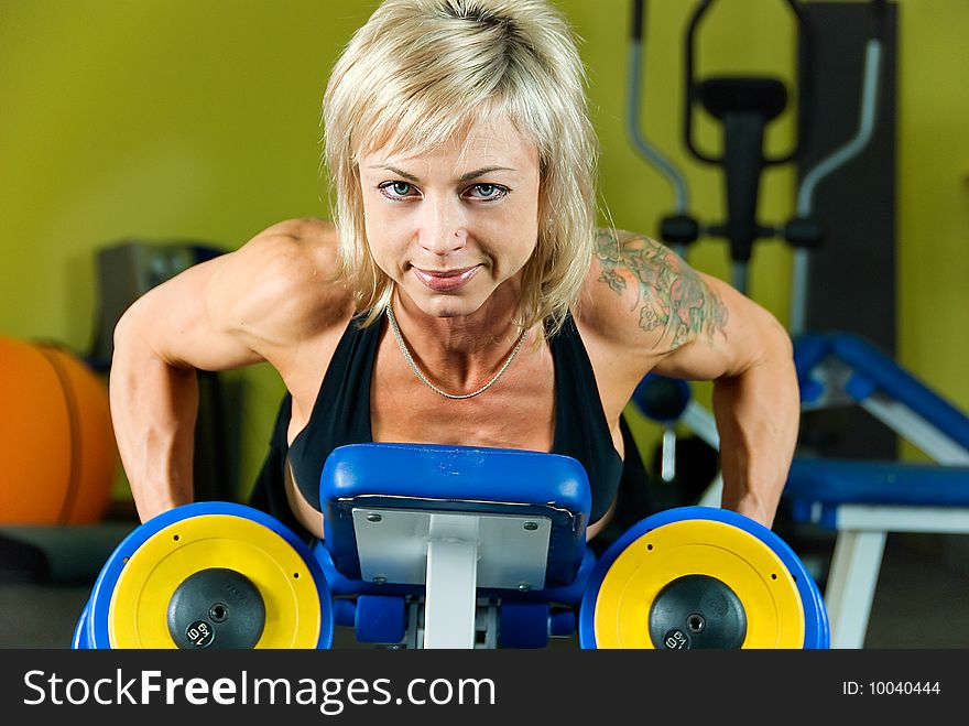 Young woman bodybuilder does exercise with dumbbells. Young woman bodybuilder does exercise with dumbbells