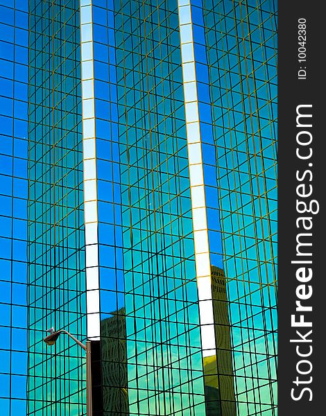 A seagull sits on a street light, dwarfed by the enormous facade of a glass skyscraper. A seagull sits on a street light, dwarfed by the enormous facade of a glass skyscraper