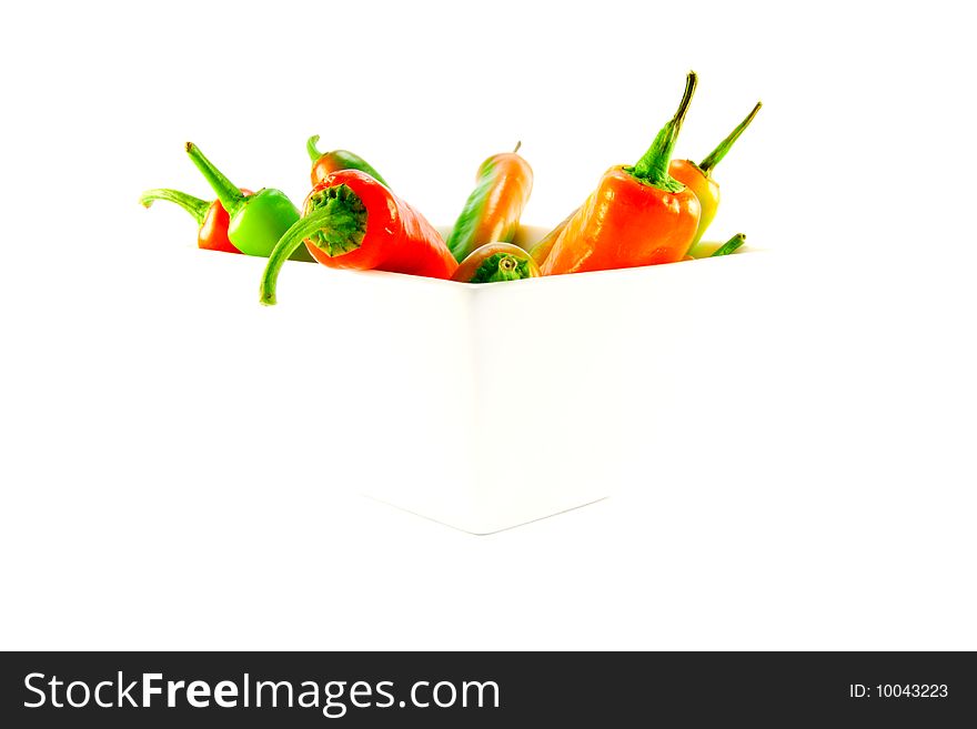 Red and green chillis in a white square bowl with clipping path on a white background. Red and green chillis in a white square bowl with clipping path on a white background
