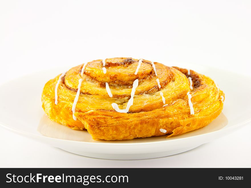 Single cinnamon bun on a plate with clipping path on a white background. Single cinnamon bun on a plate with clipping path on a white background