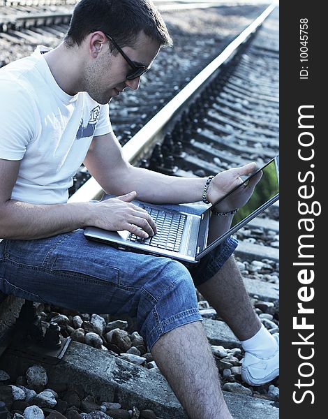 Attractive young guy with laptop on rails