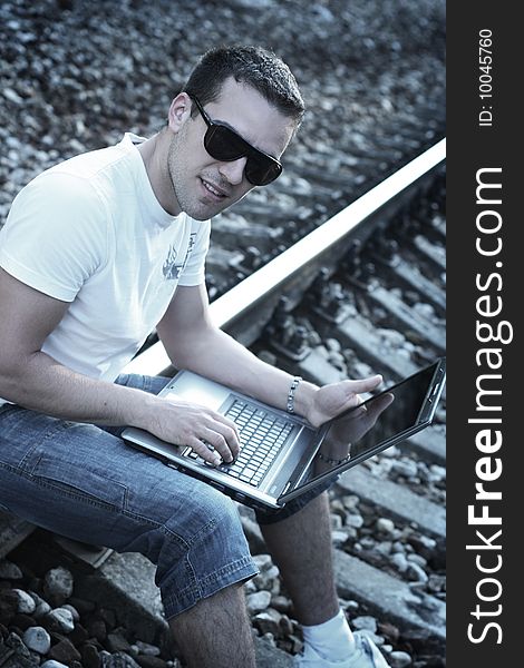 Attractive young guy with laptop on rails
