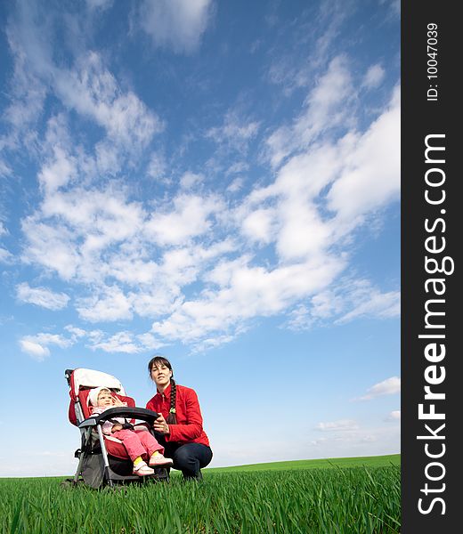 Woman with a baby-buggy in the field under blue sky with clouds. Woman with a baby-buggy in the field under blue sky with clouds