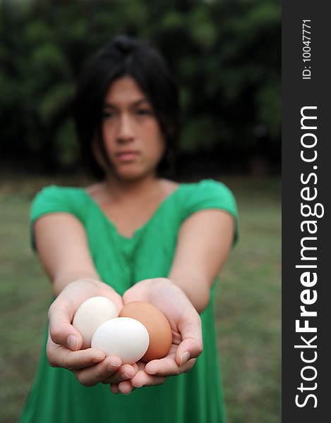 An asian girl holds some eggs, no smile. An asian girl holds some eggs, no smile.