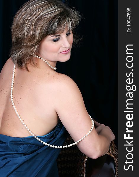 Beautiful mature female wrapped in fabric, wearing pearls