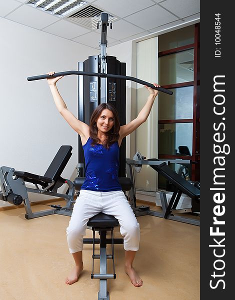 Girl is engaged on a training apparatus in sports hall. Girl is engaged on a training apparatus in sports hall