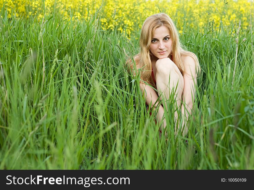 An image of a young beautiful girl sitting in the grass. An image of a young beautiful girl sitting in the grass