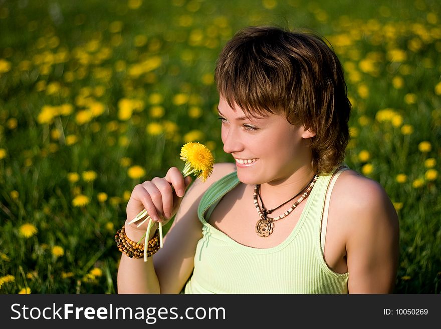 A young cheerful woman having fun on a dandelions glade