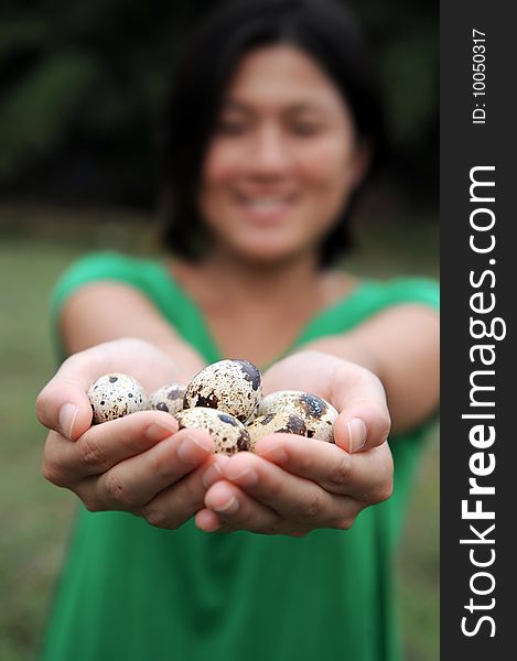 An asian girl smiles as she cradles her handful of quail eggs. An asian girl smiles as she cradles her handful of quail eggs