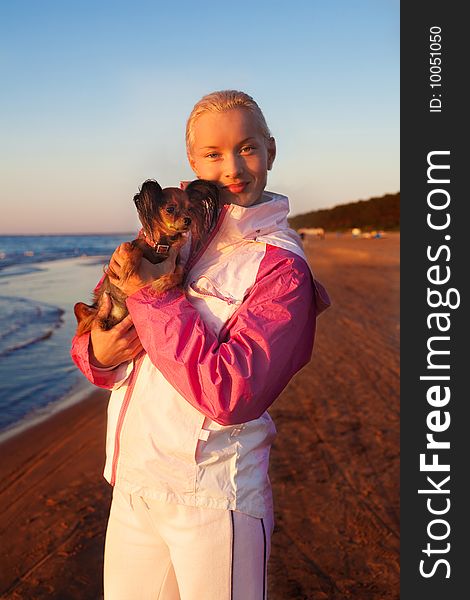 Young beautiful blonde woman with her dog on a beach