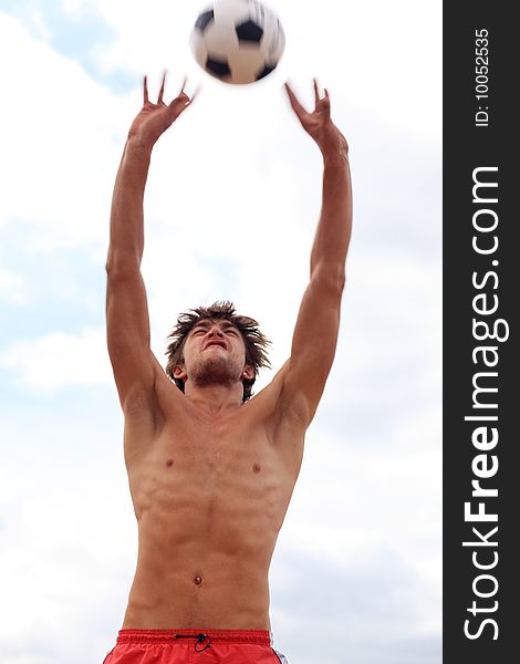 Portrait of a young man playing volleyball on a beach.