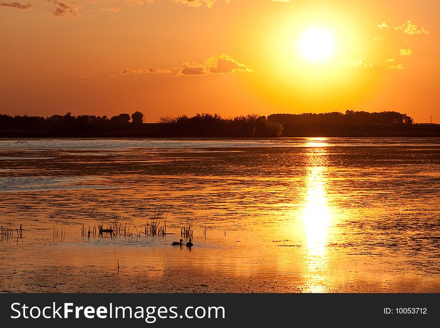 A Canadian prairie sunset on a calm pond. A Canadian prairie sunset on a calm pond.