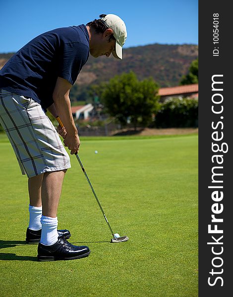 A man putting a golf ball toward the hole. A man putting a golf ball toward the hole