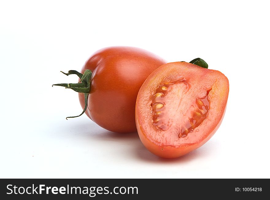 One sliced tomato in front of a whole one over a white seemless background. One sliced tomato in front of a whole one over a white seemless background.