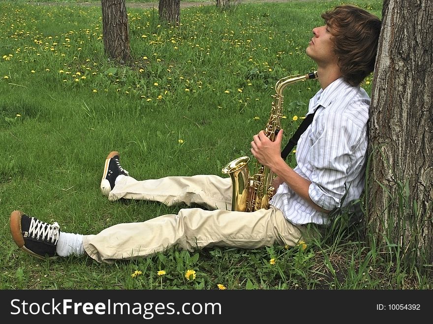 Young man with saxophone on lawn