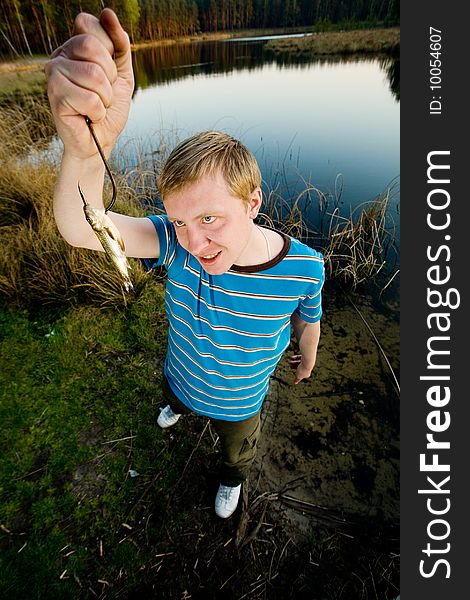 A cute guy showing off a crucian he has just caught. A cute guy showing off a crucian he has just caught