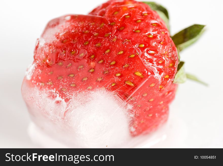 Strawberry frozen inside ice cube, melting. Shallow depth of field, selective focus. Macro shot. Extreme closeup. Strawberry frozen inside ice cube, melting. Shallow depth of field, selective focus. Macro shot. Extreme closeup.