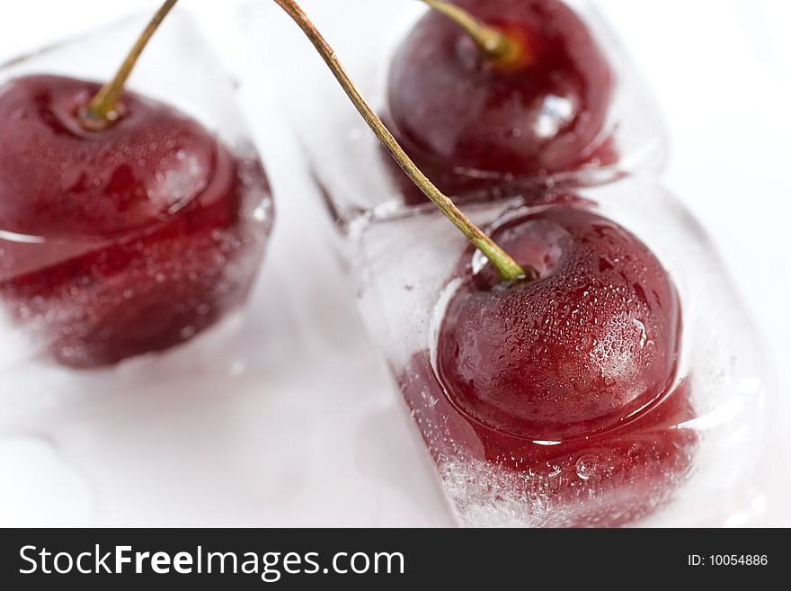 Group of cherries, frozen inside ice cubes, melting. Closeup. Shallow depth of field, selective focus. Group of cherries, frozen inside ice cubes, melting. Closeup. Shallow depth of field, selective focus.