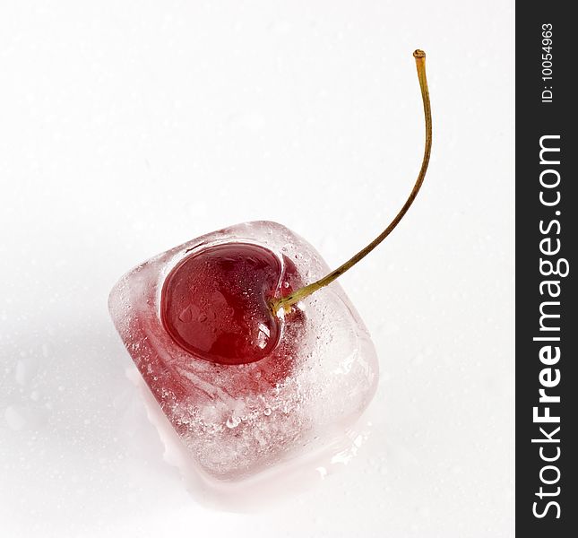 Single cherry frozen inside ice cube, melting. Single cherry frozen inside ice cube, melting.