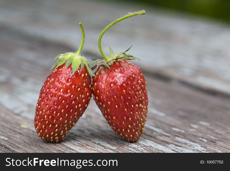 Two strawberries standing on the wooden table