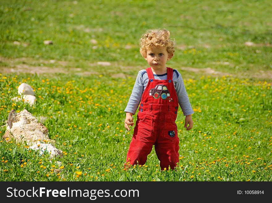 Very serious boy standing on a green grass