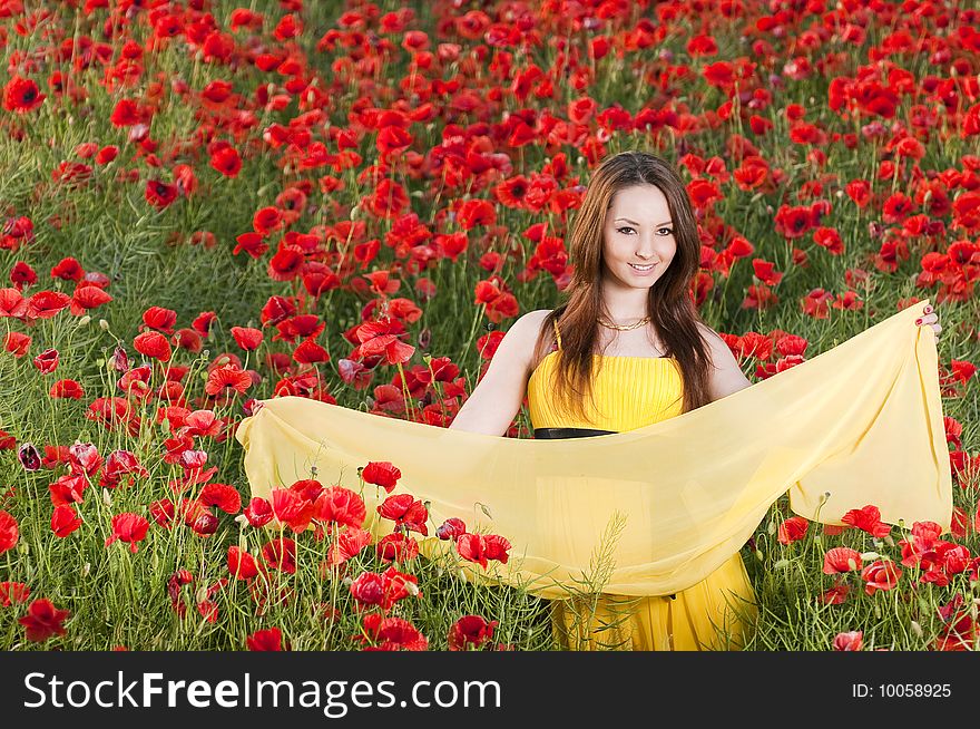 Smiling girl with yellow scarf in the poppy field