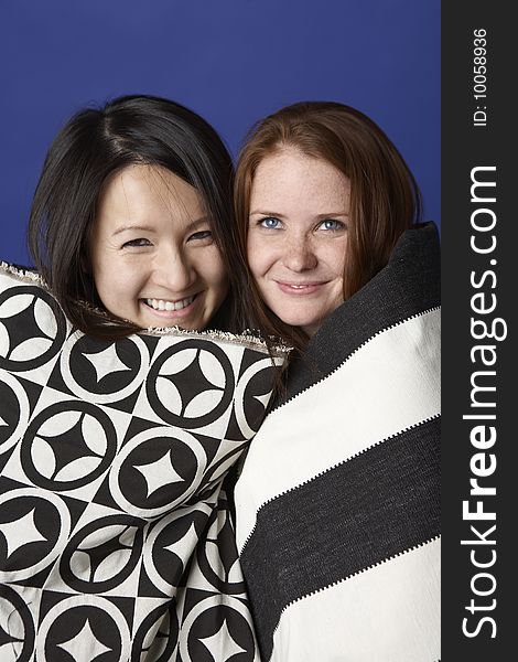 Two young women, one Asian, the other Caucasian, head to head smiling wearing black and white patterned shawls. Two young women, one Asian, the other Caucasian, head to head smiling wearing black and white patterned shawls.