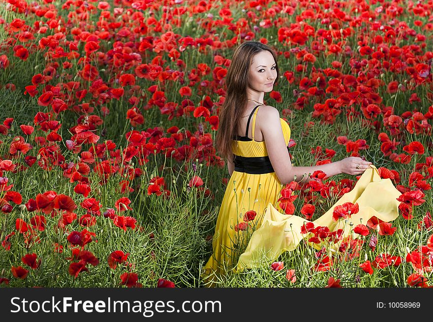 Beautiful young girl with yellow scarf in the poppy field