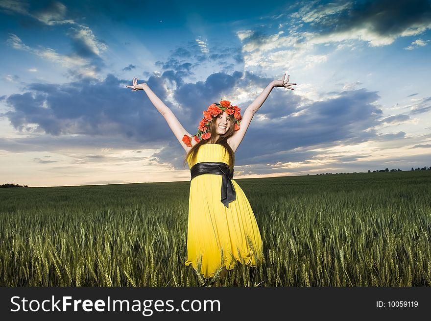 Beautiful young girl in floral wreath in the wheat field, low angle view. Beautiful young girl in floral wreath in the wheat field, low angle view