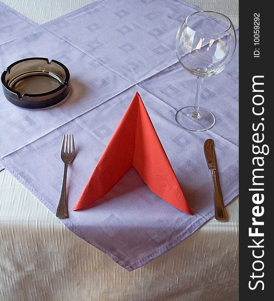 Silverware, red napkin, wine glass and ashtray on restaurant table. Silverware, red napkin, wine glass and ashtray on restaurant table