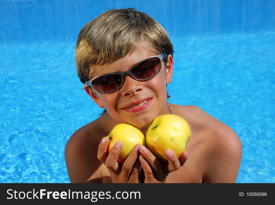 Smiling boy with sun glasses presenting apples