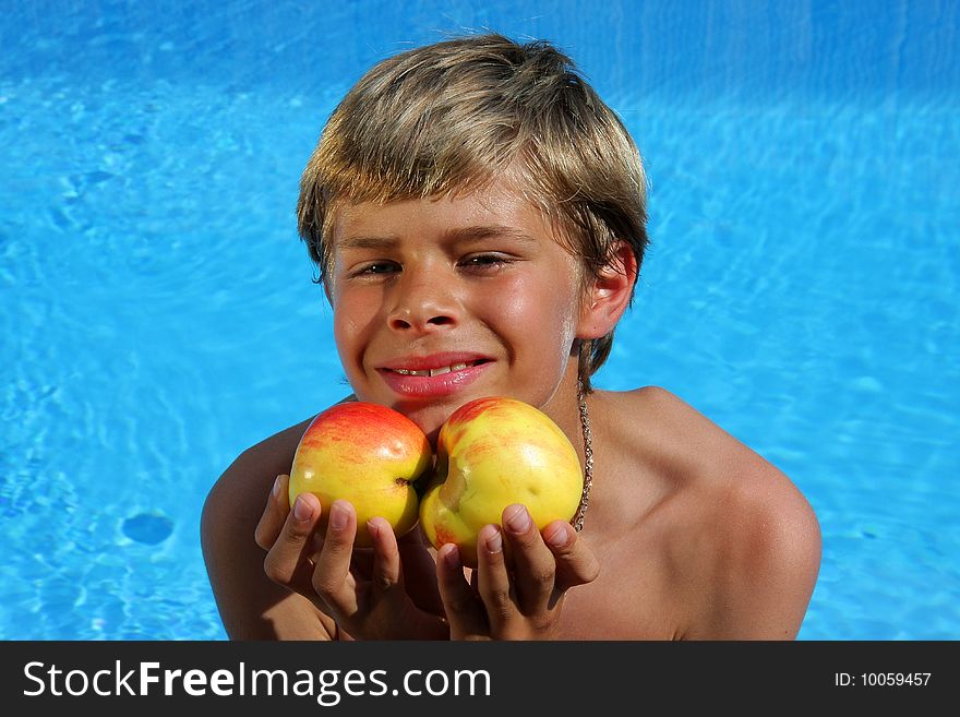 Smiling boy presenting apples at swimming pool