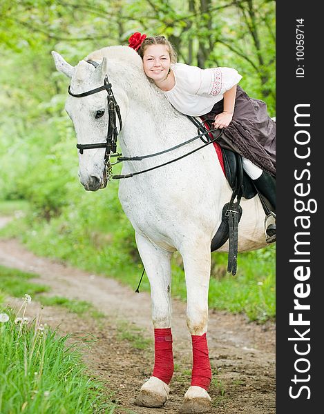 Beautiful girl riding white horse in the forest