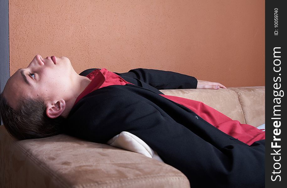 Young businessman with long hair chilling on a couch with a suit. Young businessman with long hair chilling on a couch with a suit.