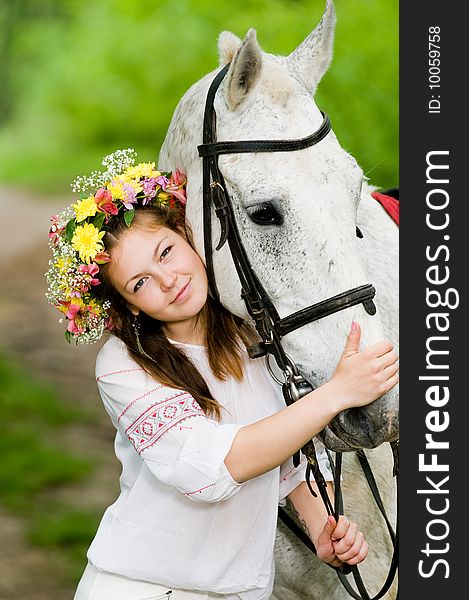 Beautiful girl in floral wreath with horse