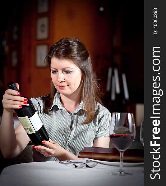 The girl chooses wine at restaurant.