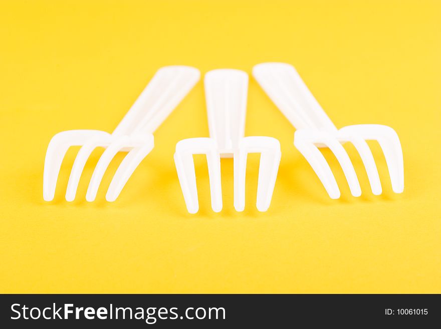 Food hunters - plastic forks isolated on yellow macro shot. Food hunters - plastic forks isolated on yellow macro shot