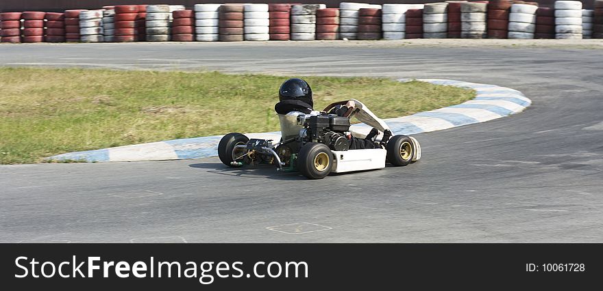 A toddler, who is actually a little bigger than the steering wheel of his kart, deftly takes the turn. A toddler, who is actually a little bigger than the steering wheel of his kart, deftly takes the turn.