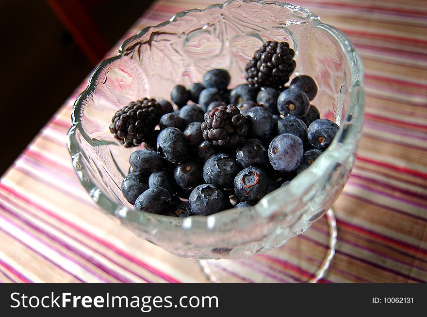 Blueberries and blackberries in a glass bowl.