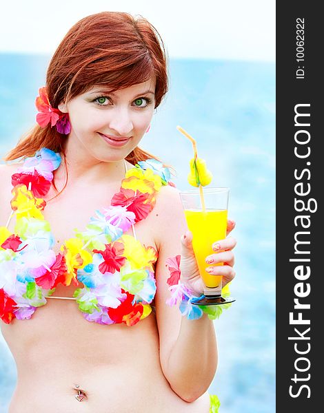 Attractve girl in bright bikini with glass of juice on sea background