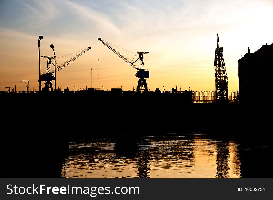 Silhouettes of Portal Cranes in a Harbor. Shot during sunset. Silhouettes of Portal Cranes in a Harbor. Shot during sunset.