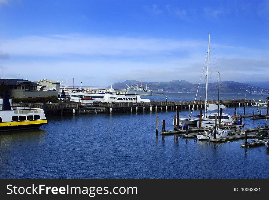 San Francisco Pier with boats and mountains in background.