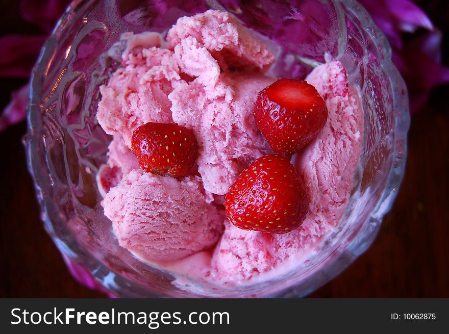 Strawberry ice cream with fresh strawberries in a glass bowl.