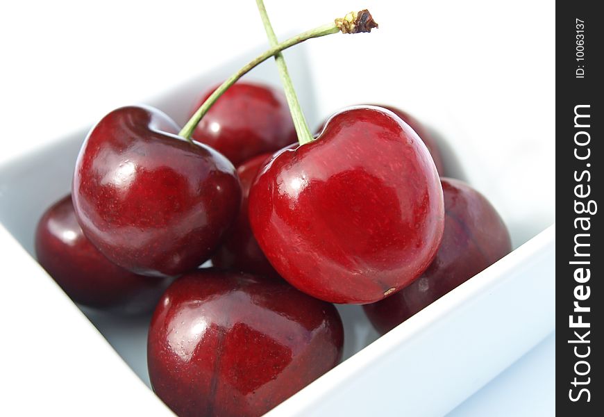 Bunch of cherries in dish against white background