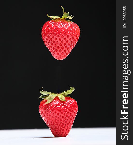 Two strawberries one suspended in air. Two strawberries one suspended in air