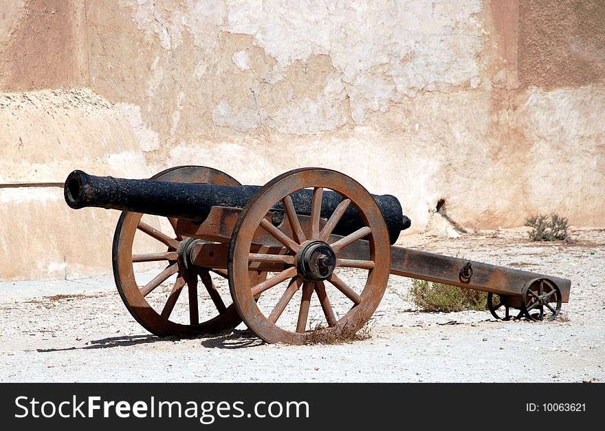 A cannon on guard next to a wall. A cannon on guard next to a wall