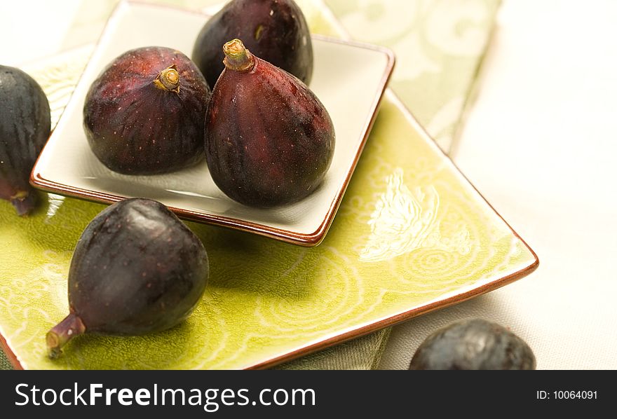 Several black figs on on green plate with napkin