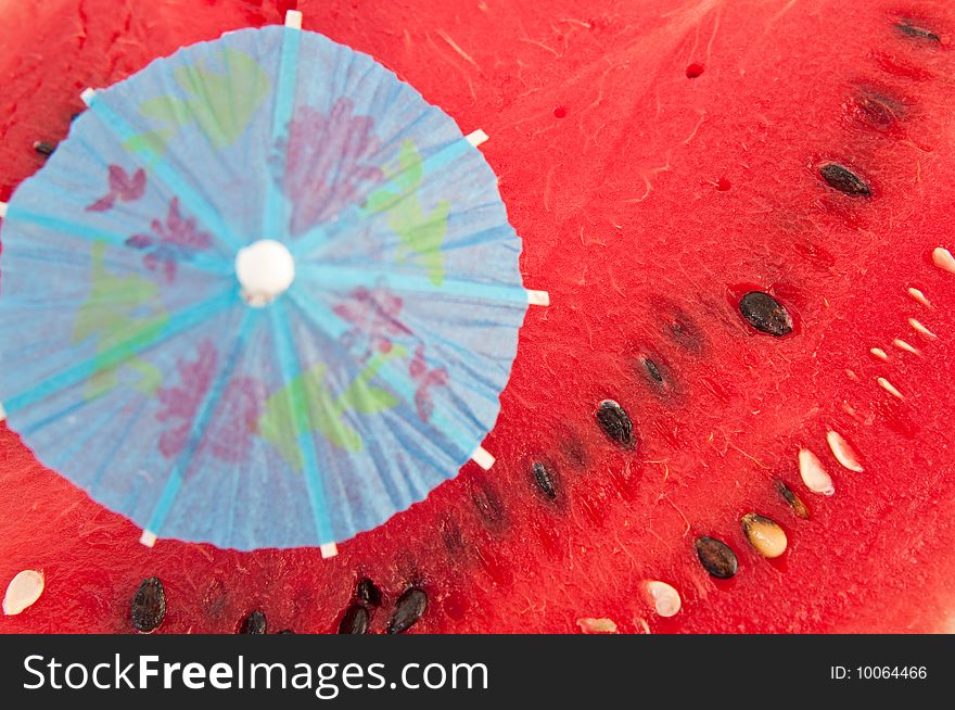 Blue umbrella will thrust in red pulp of a water-melon. Blue umbrella will thrust in red pulp of a water-melon